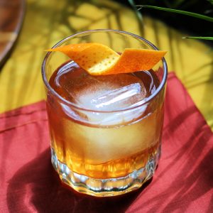Bourbon and Cascadia Liqueur cocktail served on a large cube with an orange twist