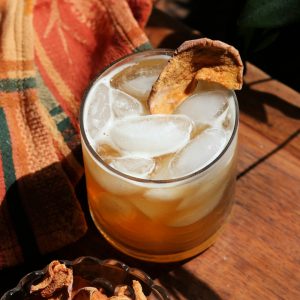 Baked apple sour cocktail on ice with a dried apple garnish made with New Deal Spiced Rum