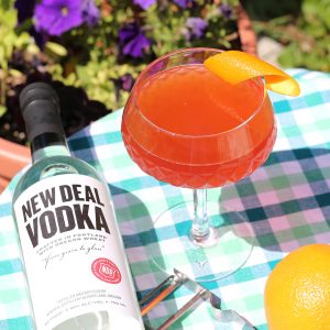 cosmo with an orange twist and bottle of new deal vodka