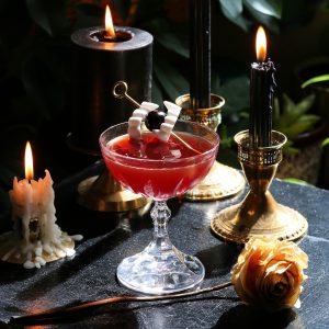 vampire kiss halloween cocktail served up with a cherry skewered through vampire teeth