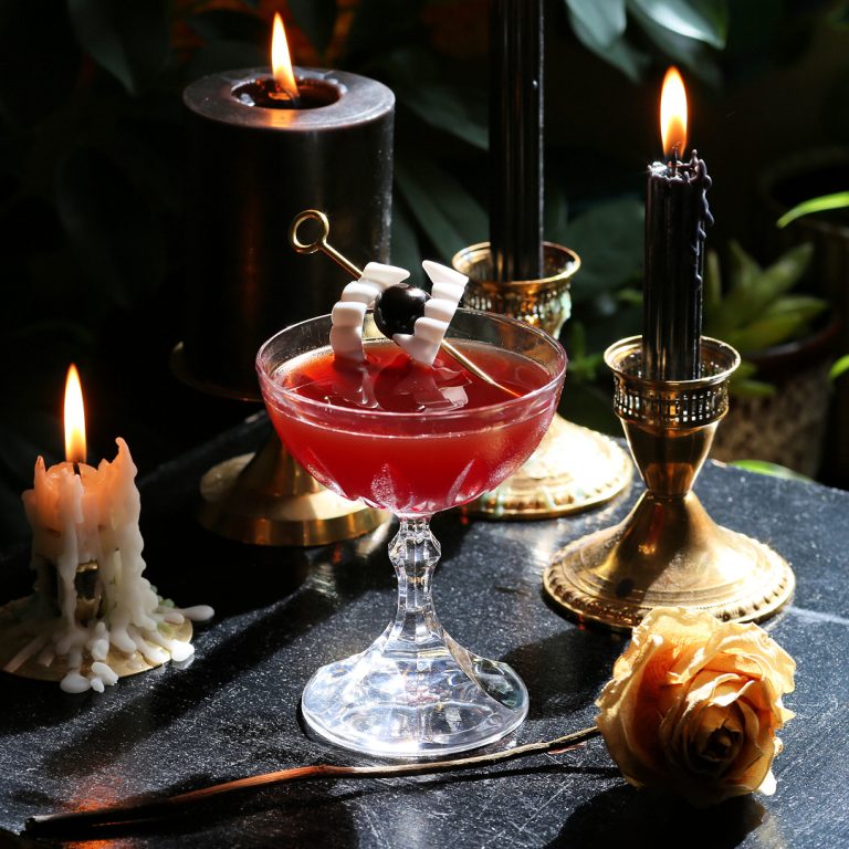 vampire kiss halloween cocktail served up with a cherry skewered through vampire teeth